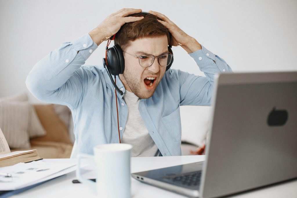Guy sitting at his computer looking shocked and angry