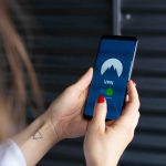 Woman holding a phone looking at a VPN app