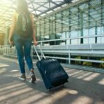 Woman outside of an airport with her luggage