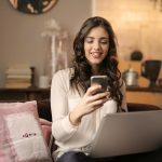 Woman shopping on her laptop and holding her phone